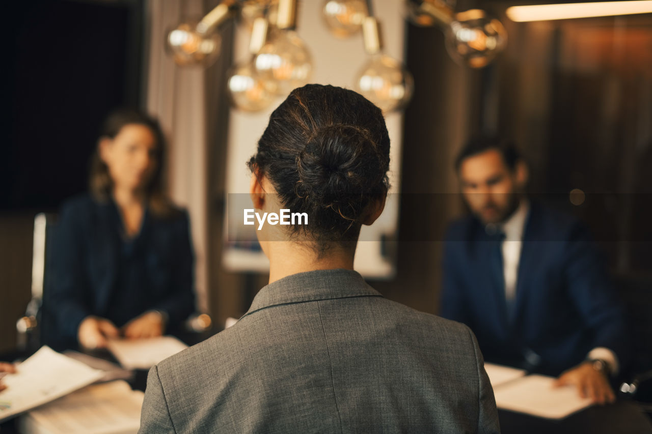 Rear view of female lawyer with colleagues in meeting at legal office