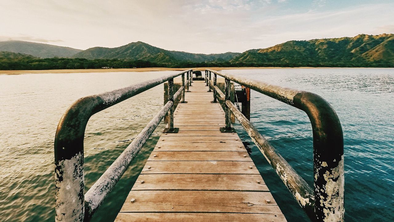 Pier over lake in front of mountains against sky