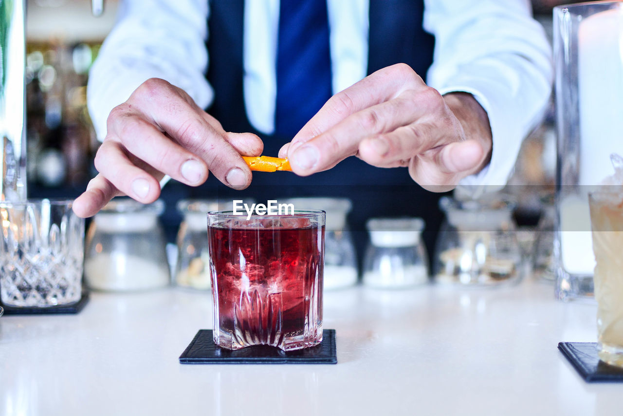 Midsection of bartender preparing a negroni at restaurant