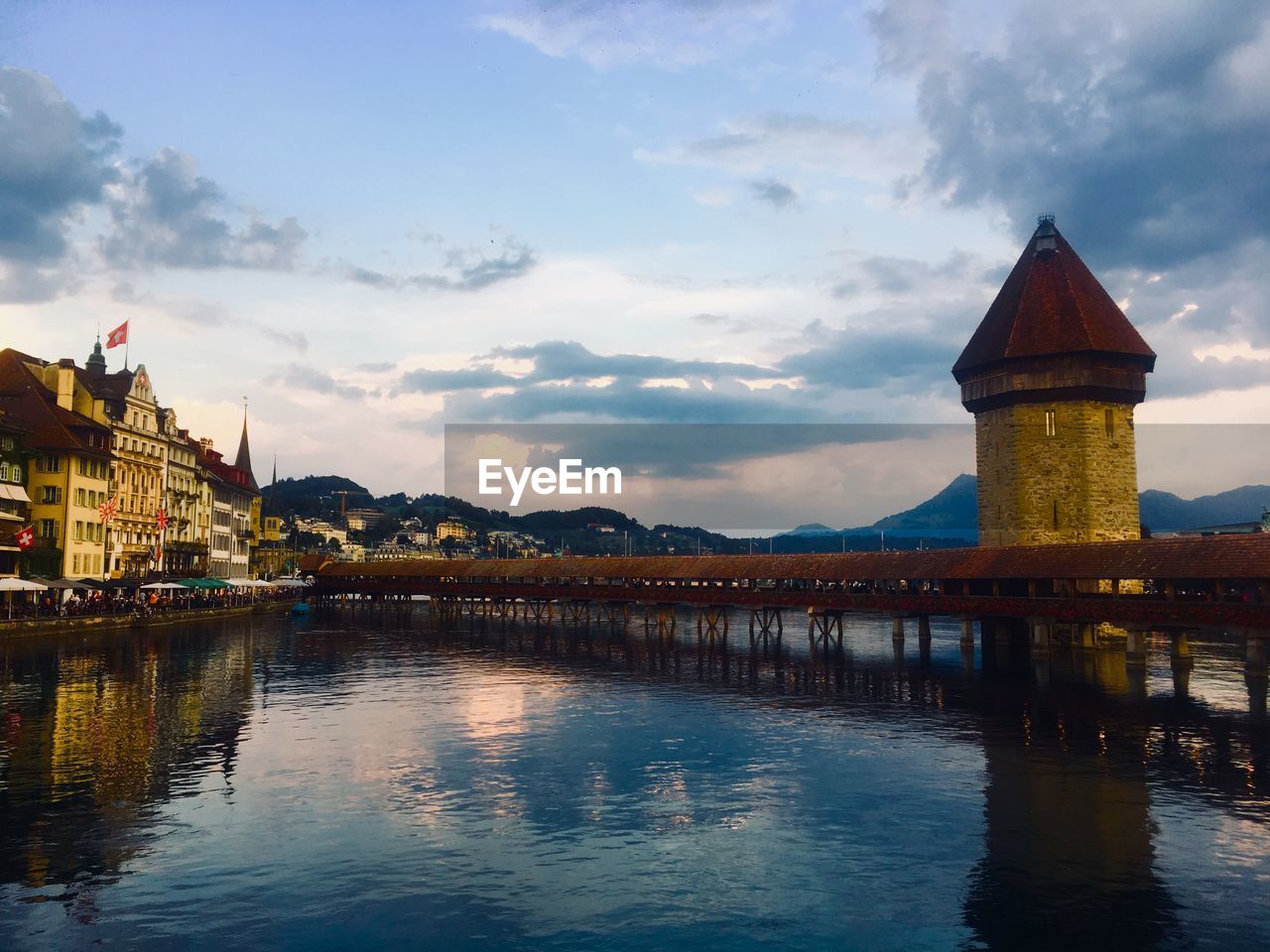 Bridge over river by buildings against sky