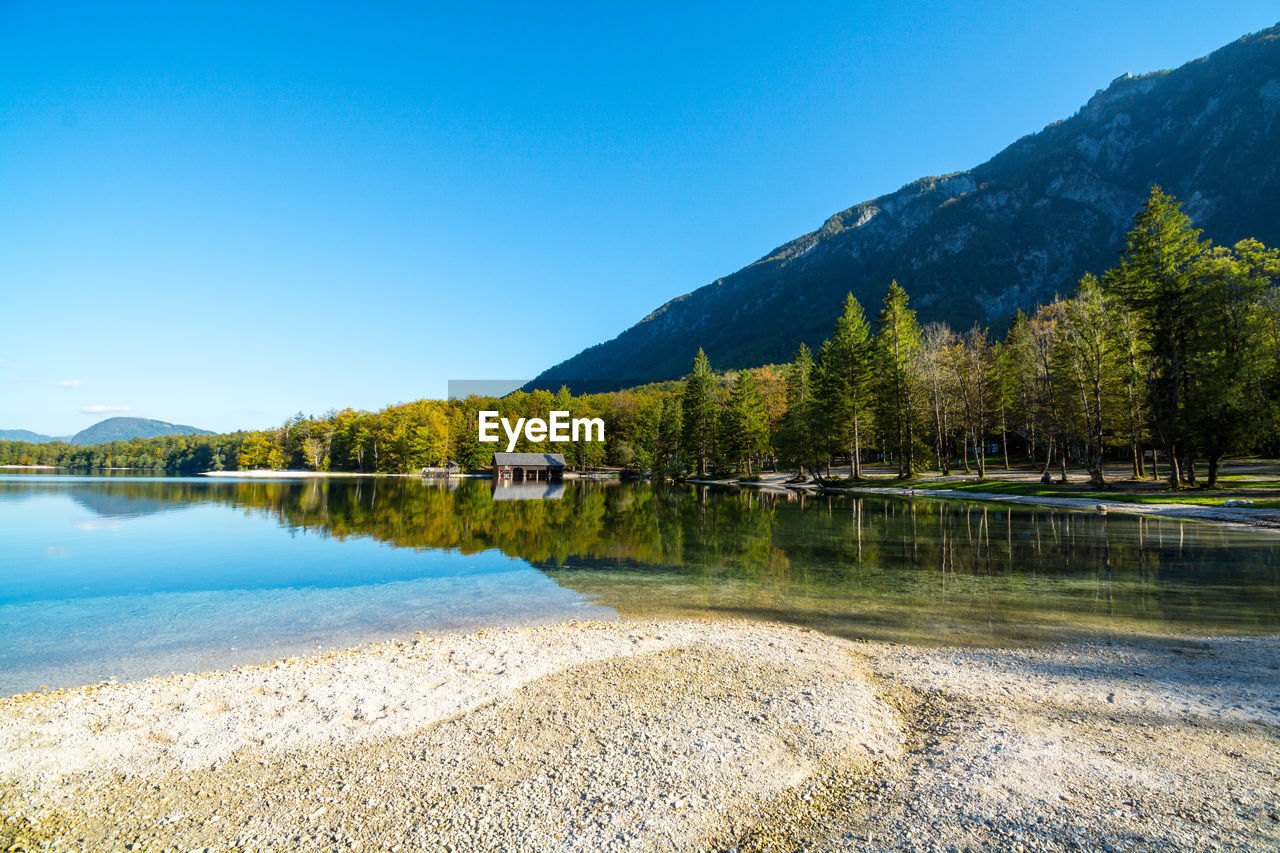 Scenic view of lake and mountains against clear blue sky