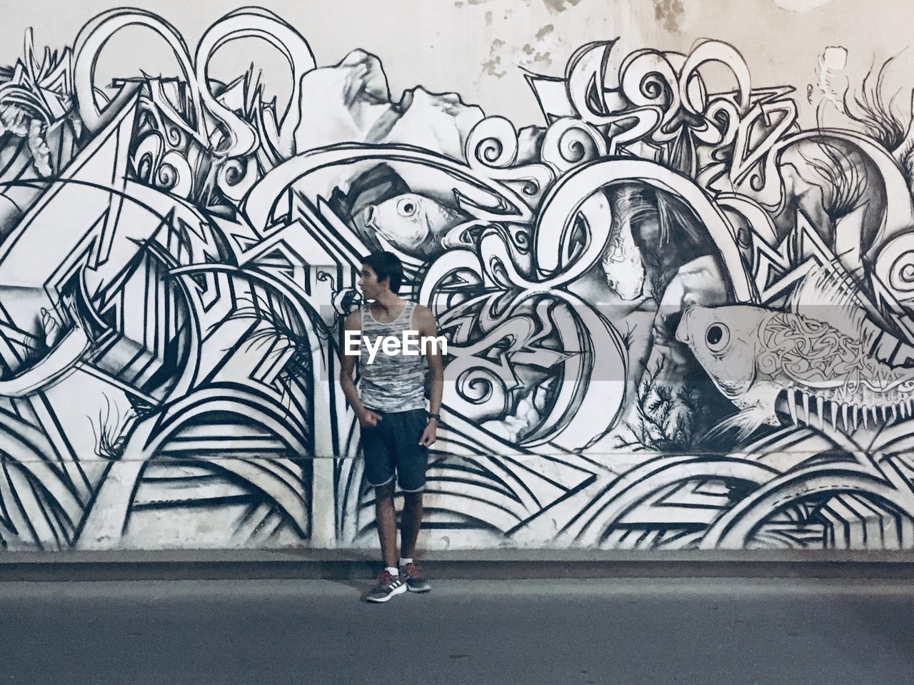 FULL LENGTH OF MAN STANDING ON GRAFFITI WALL