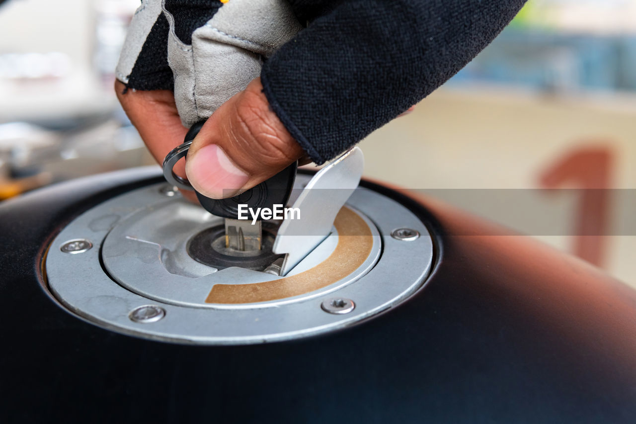 Close-up of person putting key in motorcycle