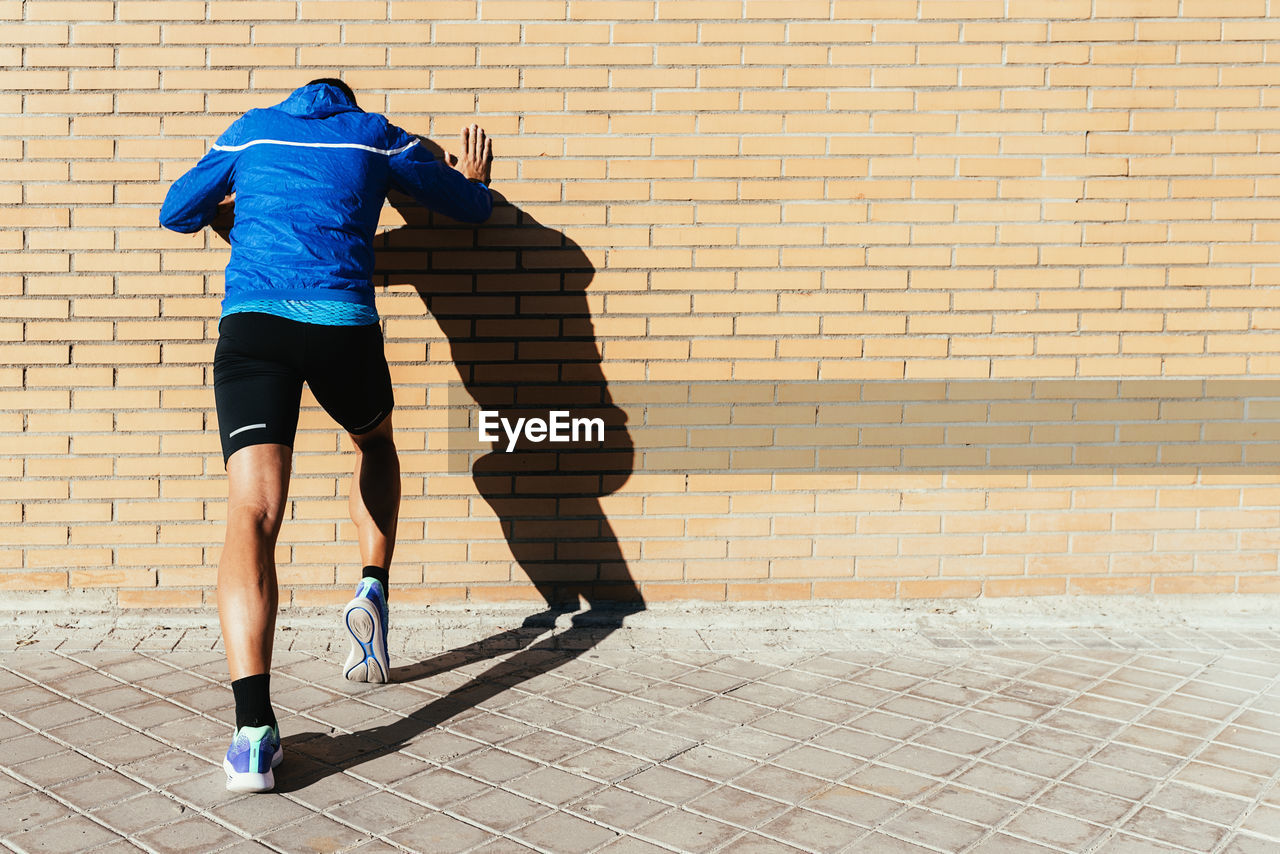 Rear view of man exercising on footpath