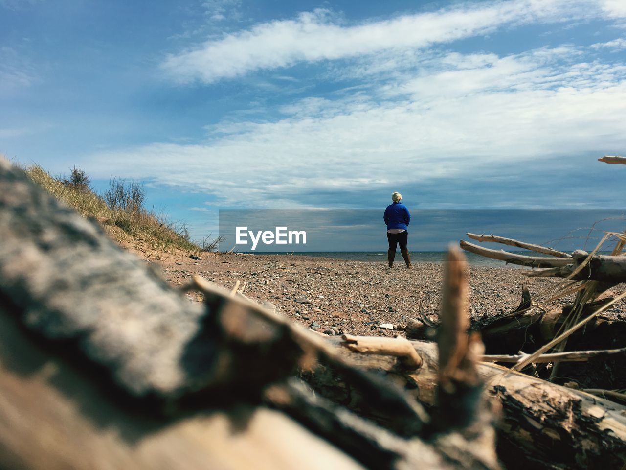 Rear view of young woman standing at beach against sky