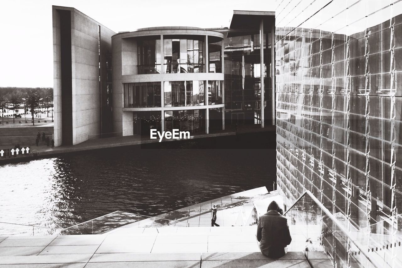 Rear view of person sitting on staircase against office building