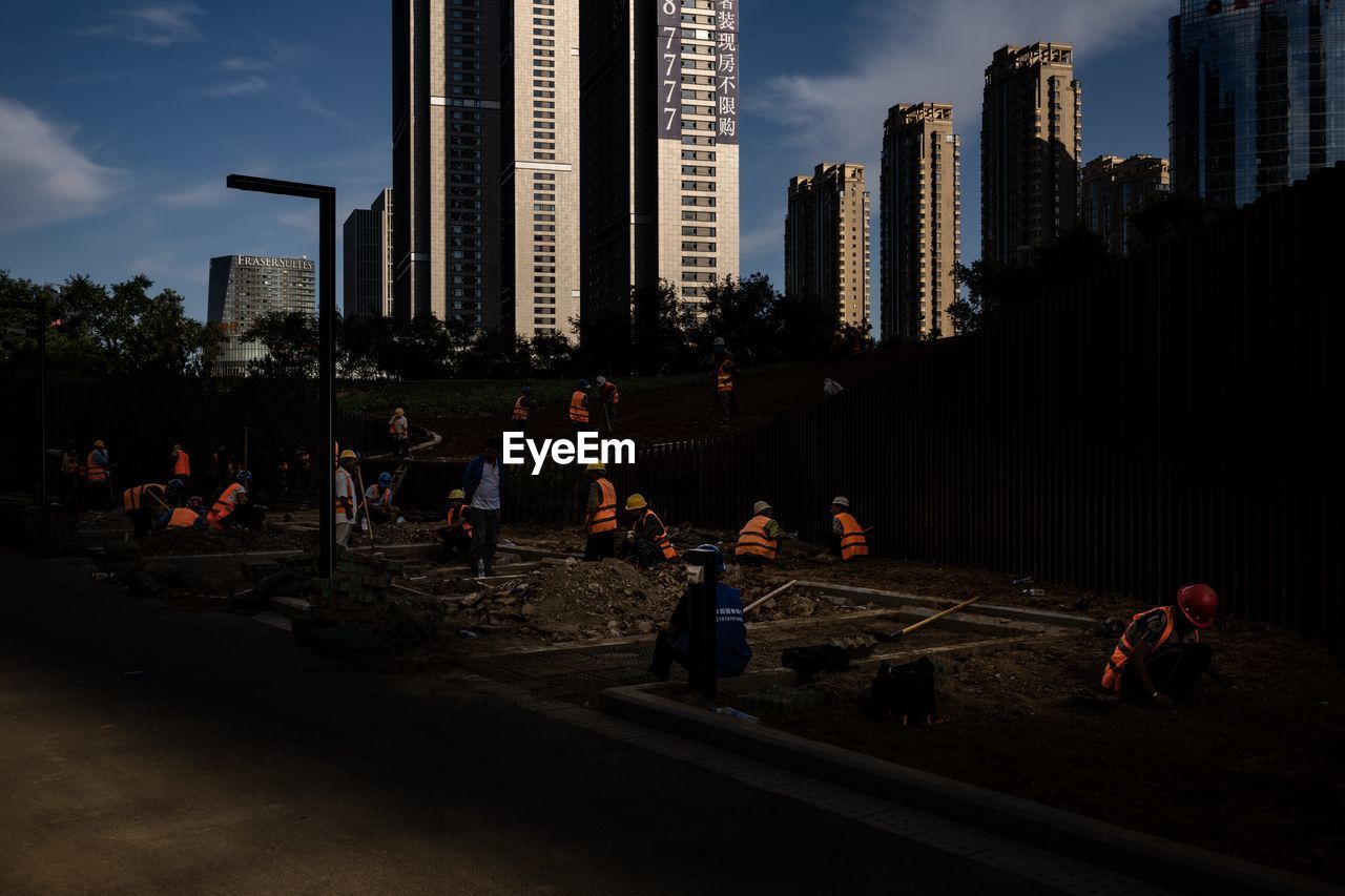 GROUP OF PEOPLE IN MODERN BUILDINGS AGAINST SKY