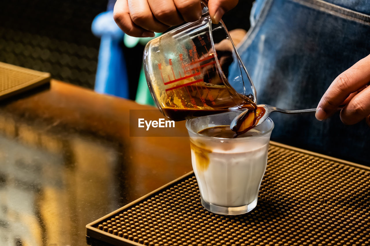 CLOSE-UP OF HAND POURING TEA IN GLASS