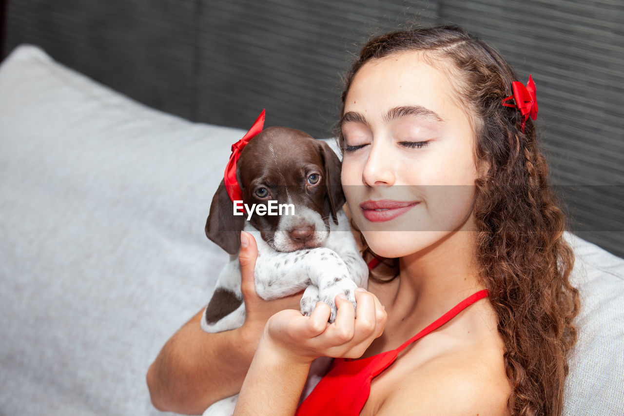 Beautiful young girl dressed in red with her small french braque puppy