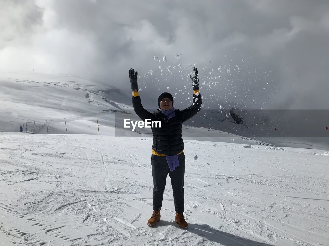 Full length of woman playing with snow on mountain