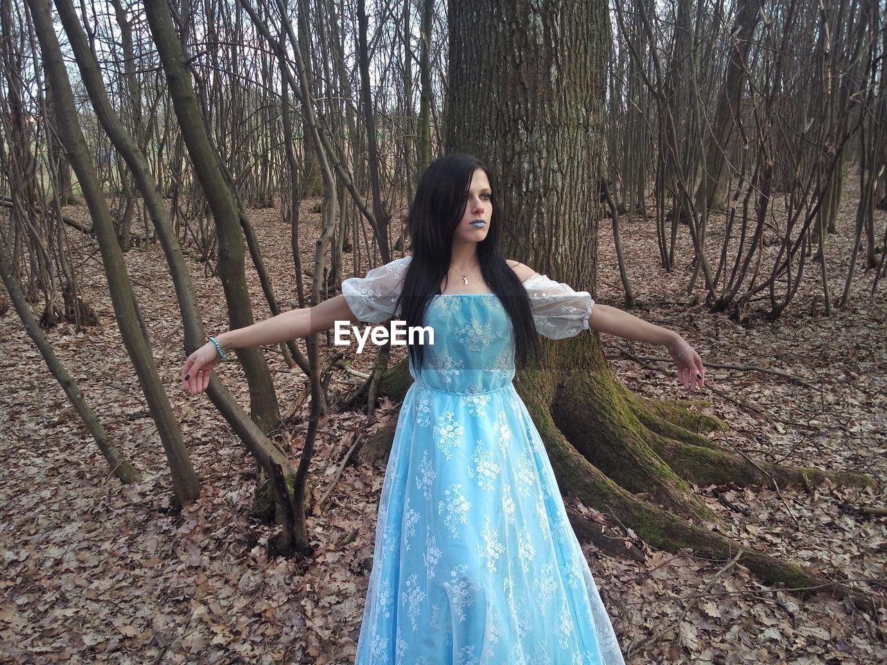 YOUNG WOMAN STANDING IN FOREST