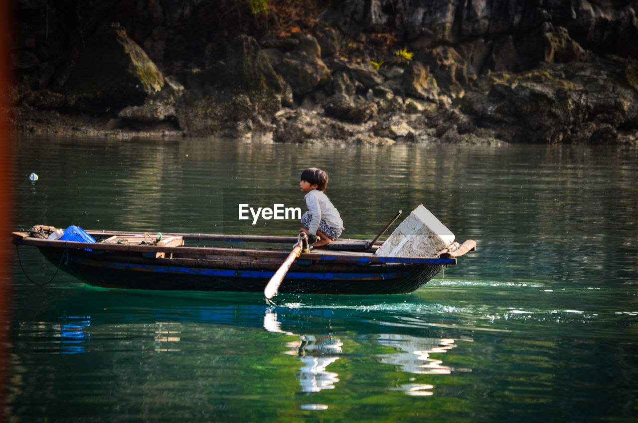 PEOPLE SITTING ON BOAT IN LAKE