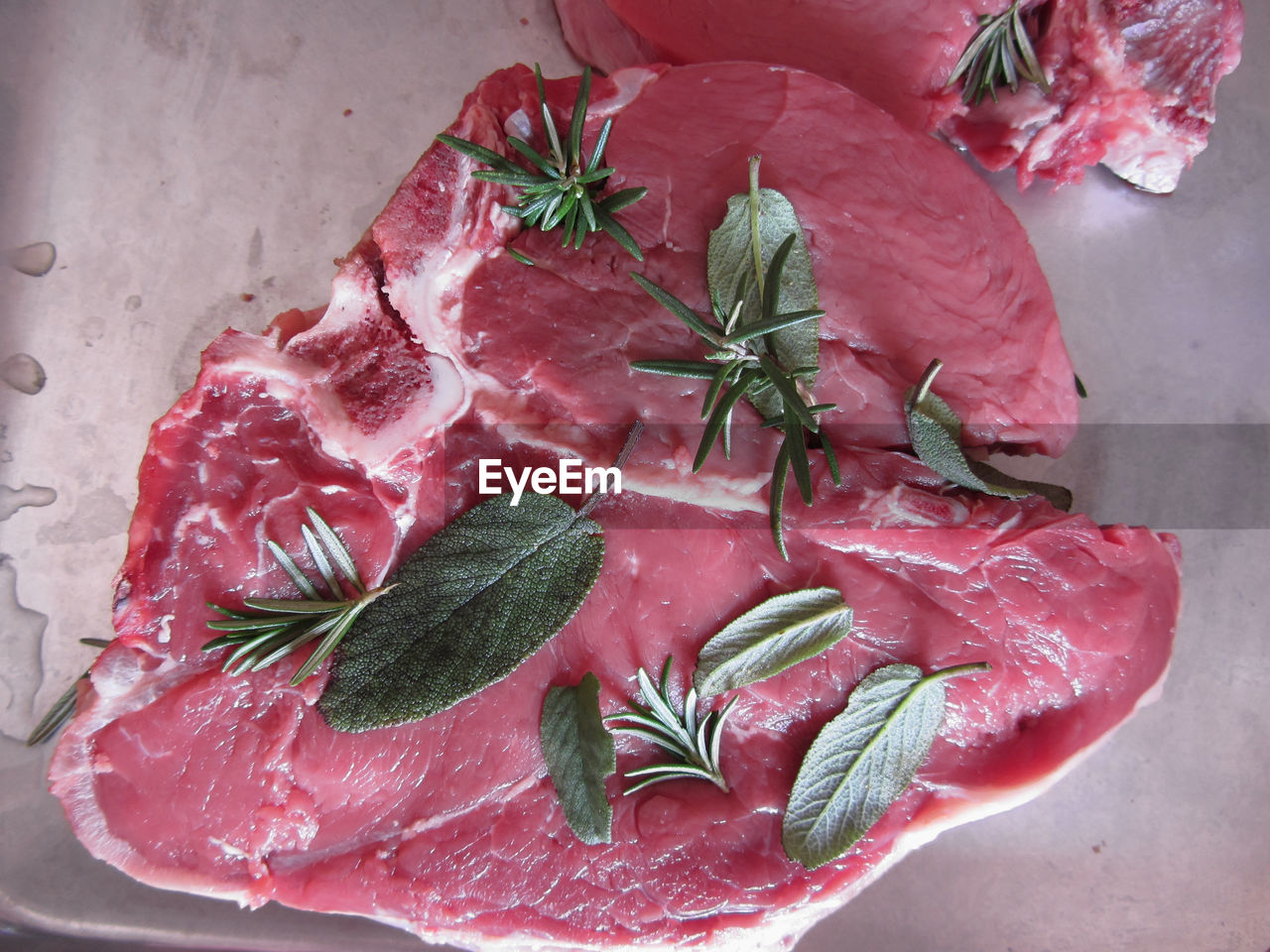 Fresh raw marbled meat steak with sage and rosemary ready to be cooked in the oven