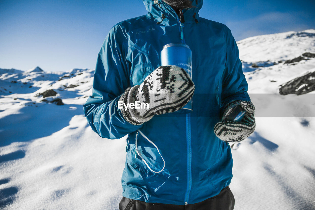 PERSON WITH UMBRELLA AGAINST SNOWCAPPED MOUNTAINS