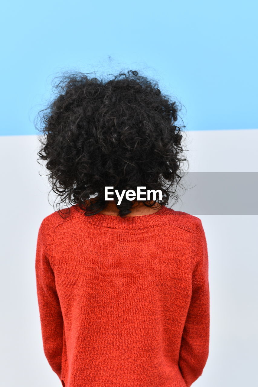 Rear view of woman with curly hair standing against white background