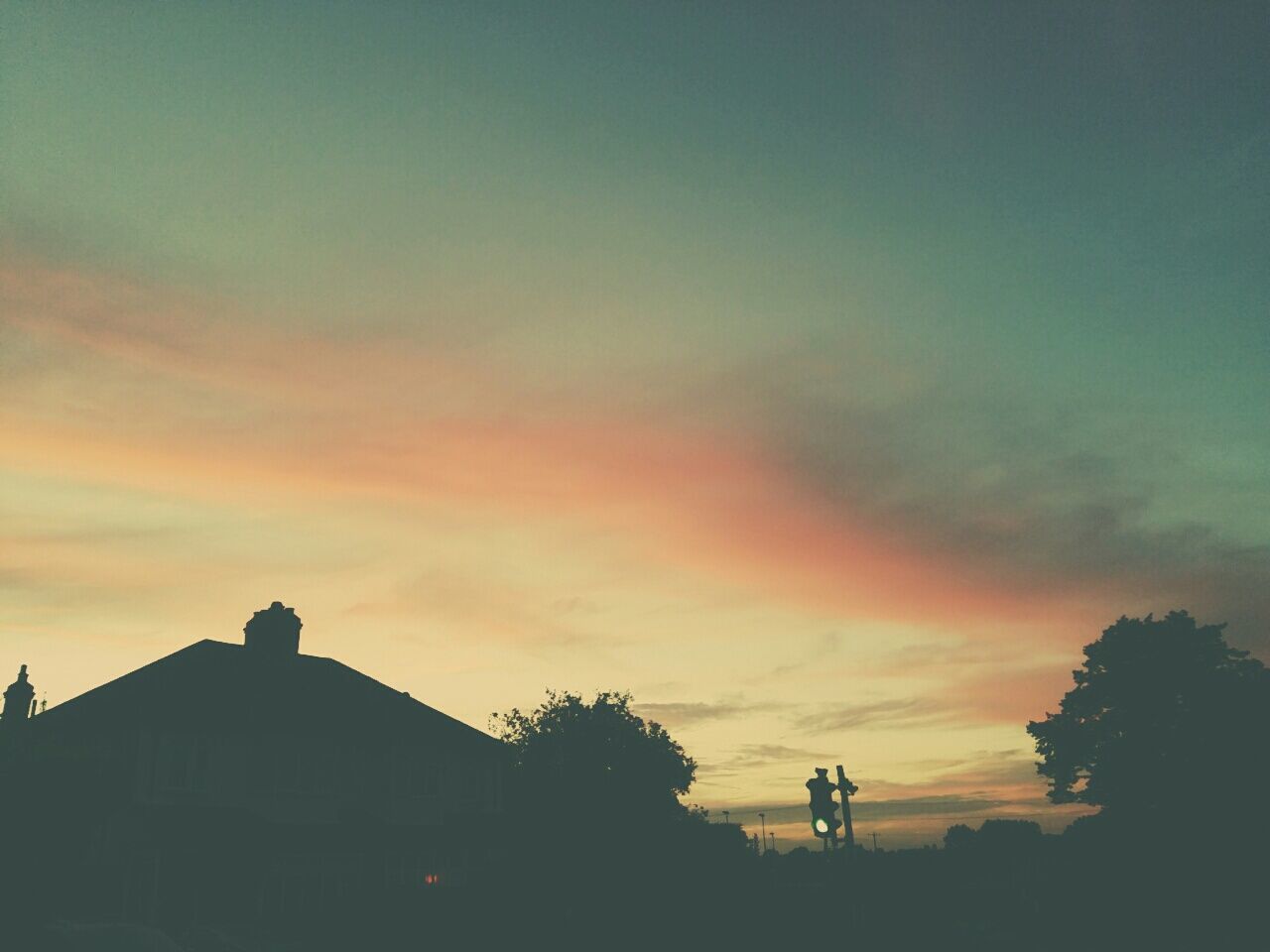 Silhouette house against sunset sky
