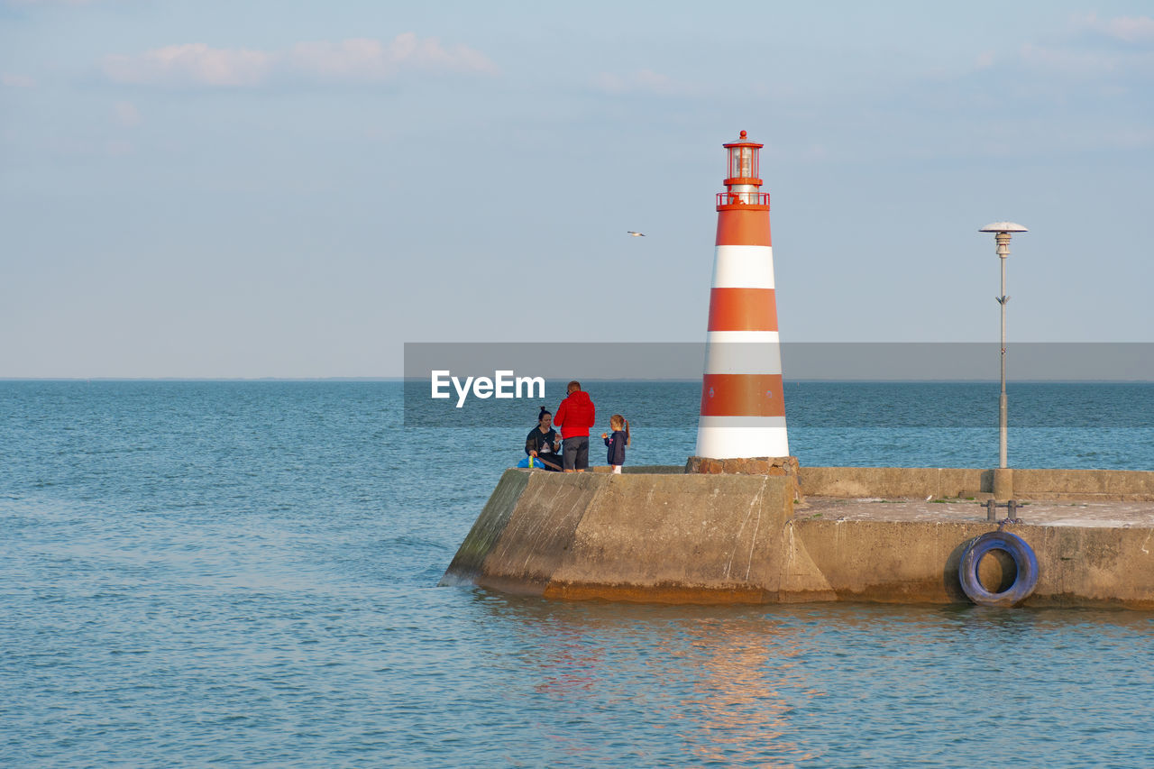 LIGHTHOUSE ON SHORE AGAINST SKY