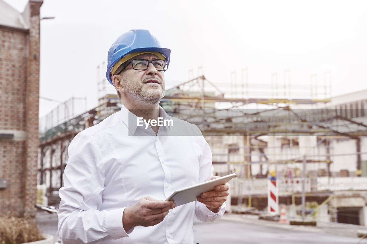 Portrait of smiling man with tablet wearing blue hart hat