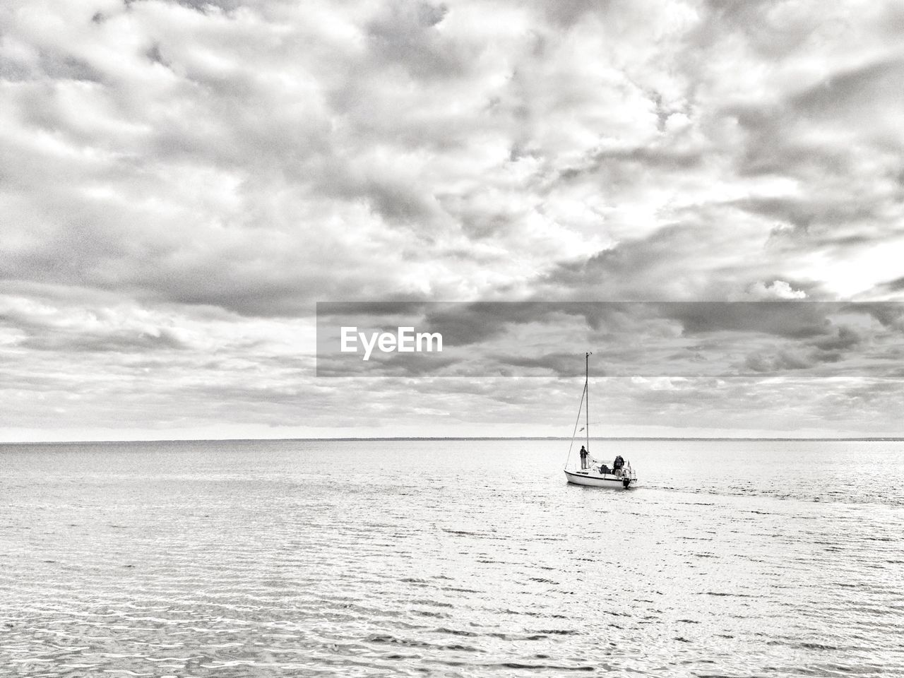 Lone boat in calm sea against clouds