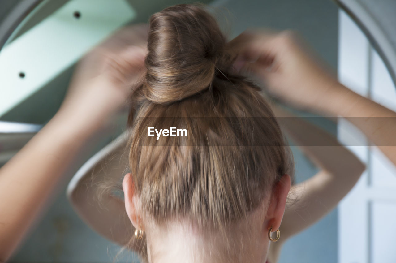 Rear view of woman tying hair while standing at home