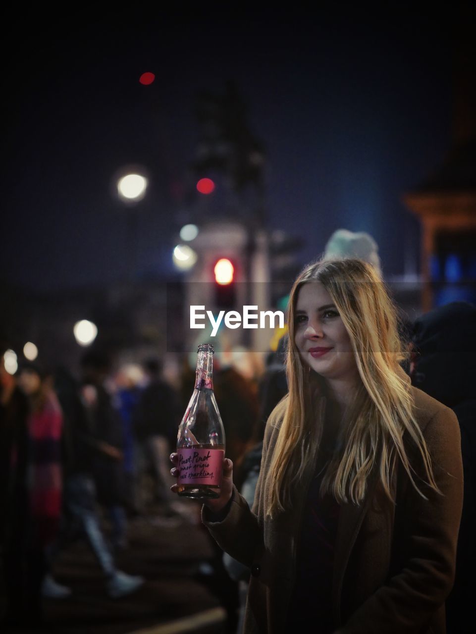 YOUNG WOMAN WITH DRINK IN GLASS AT NIGHT DURING FESTIVAL