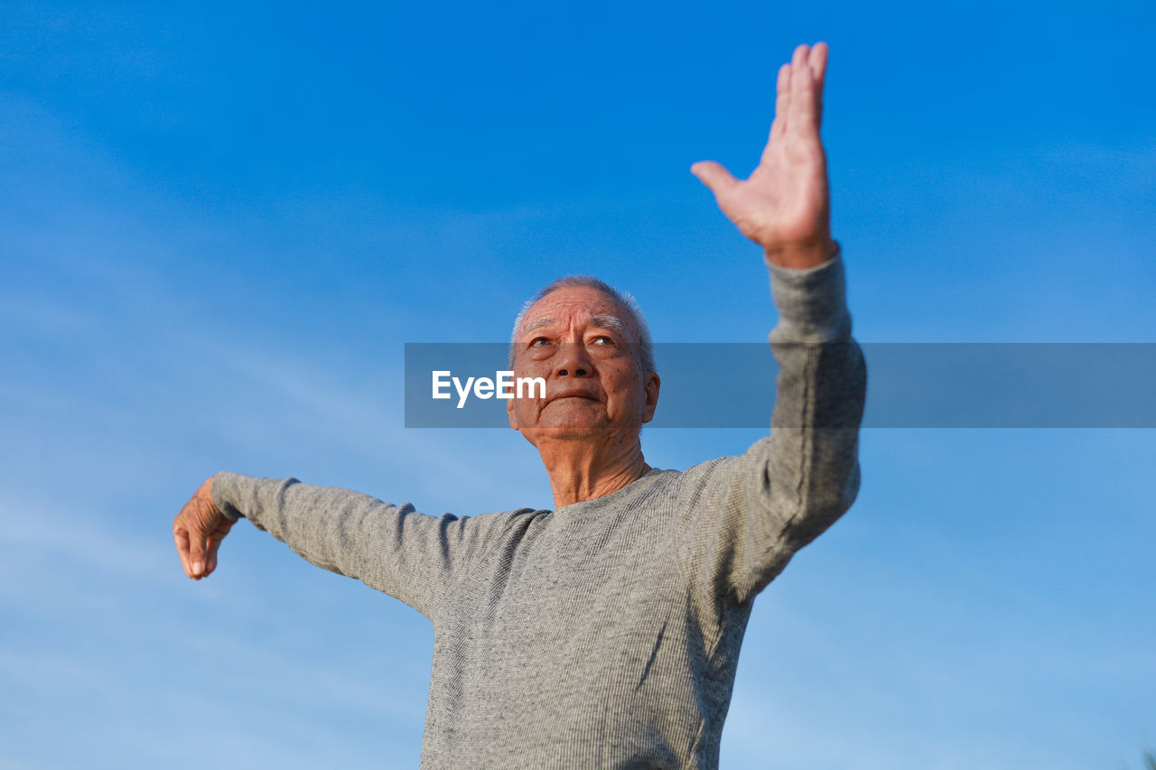 LOW ANGLE VIEW OF MAN WITH WOMAN AGAINST BLUE SKY