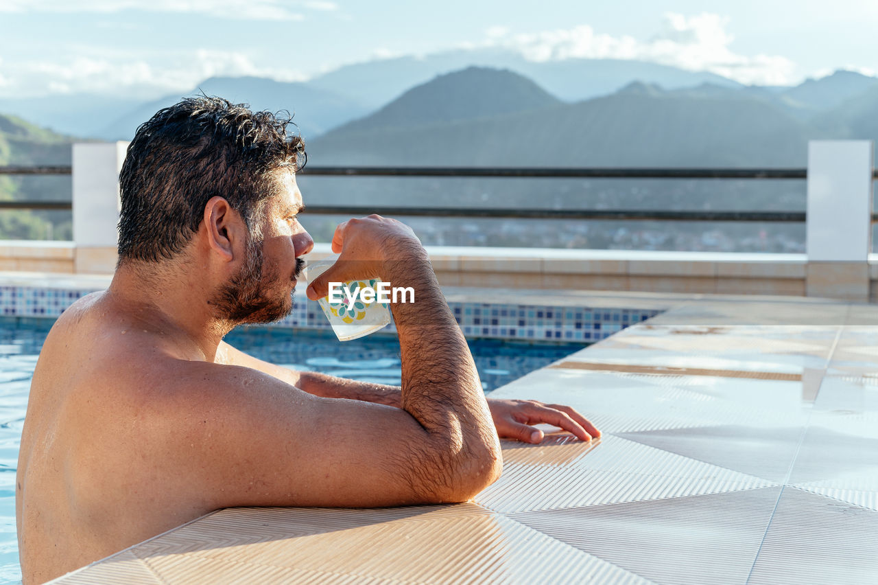 Man drinking in a pool enjoying the view 