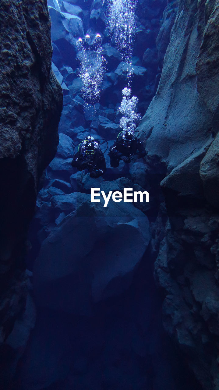 Scuba divers swimming in underwater cave