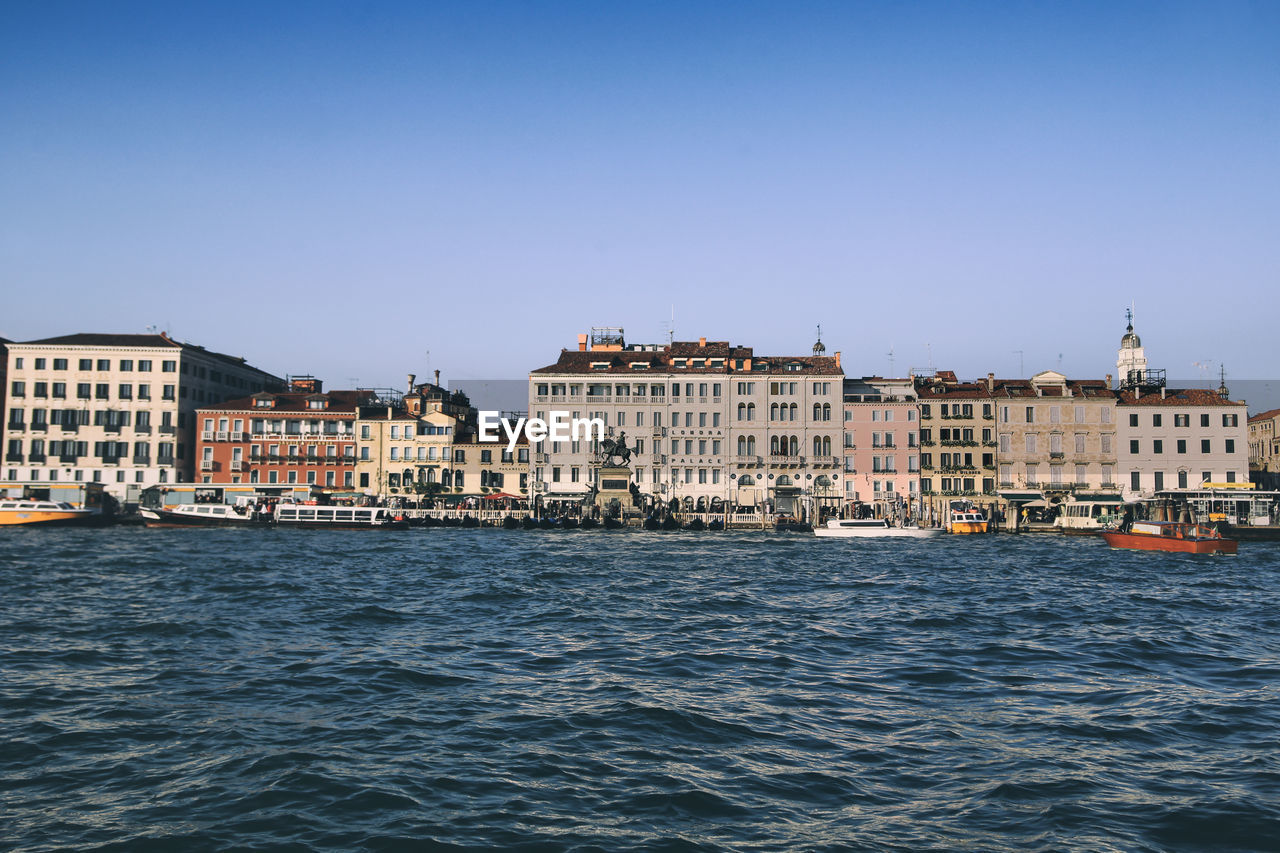 View of buildings by sea against clear sky