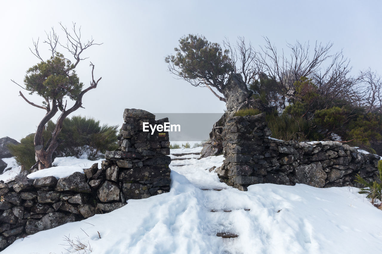 Stone wall surrounded by snow in pico ruivo footpath in santana, madeira island