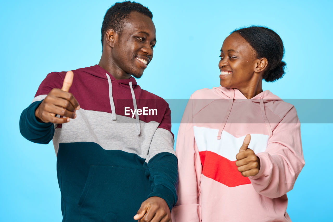 Couple standing against colored background