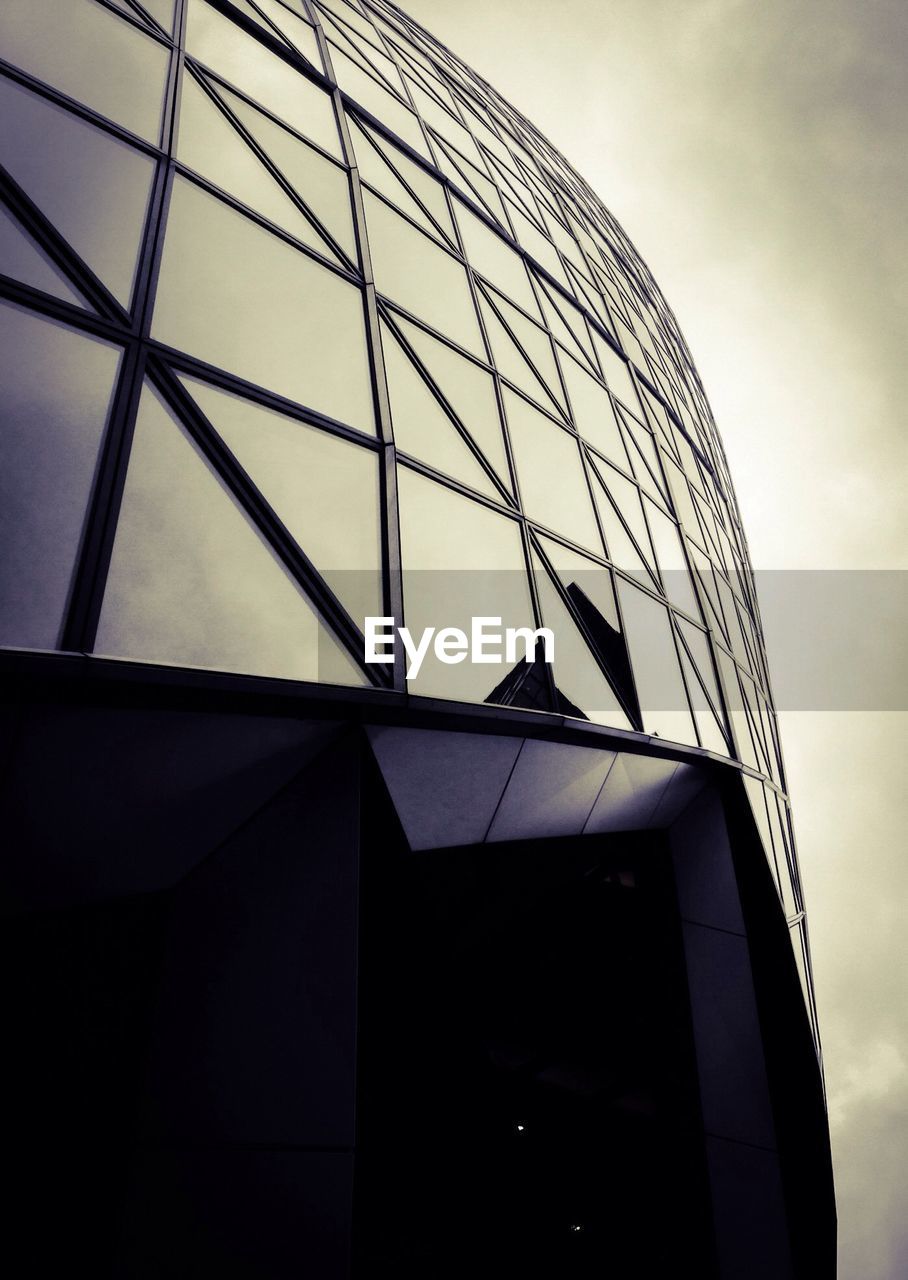 Low angle view of sir norman foster building against cloudy sky