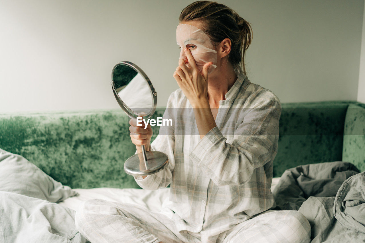 A woman makes a caring beauty procedure at home, a moisturizing cosmetic face mask.