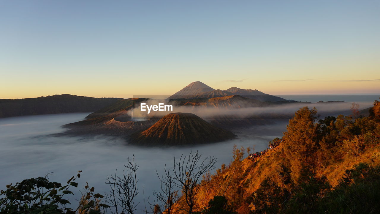 sky, sunrise, morning, dawn, nature, mountain, beauty in nature, scenics - nature, wilderness, volcano, landscape, water, land, environment, reflection, no people, plant, travel destinations, tranquility, tree, tranquil scene, non-urban scene, lake, travel, outdoors, twilight, clear sky, horizon, tourism, volcanic landscape, idyllic, sunlight, geology, volcanic crater, mountain peak, blue, cloud