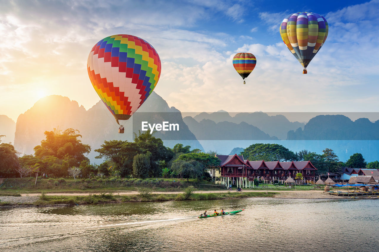 Hot air balloons flying over lake against sky