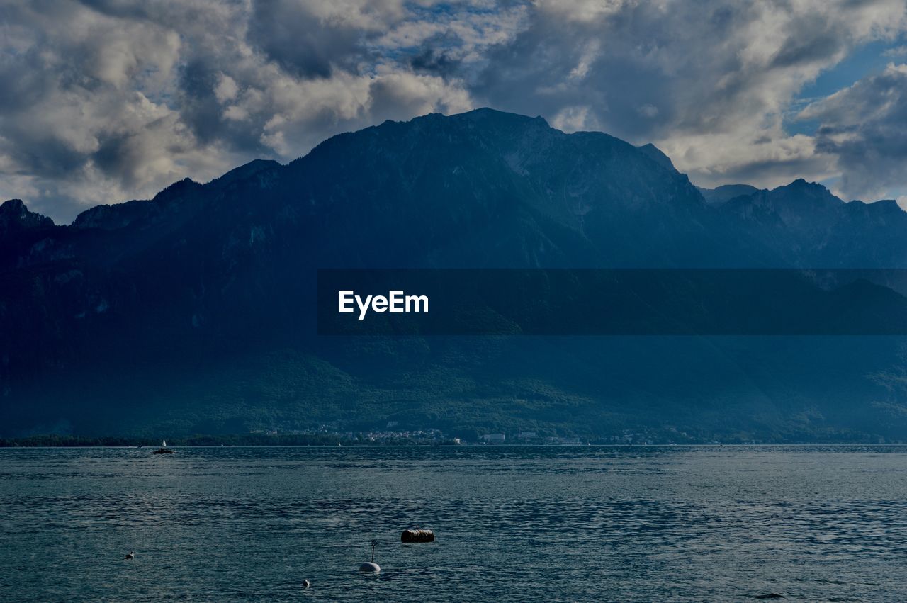 Scenic view of sea by mountains against sky