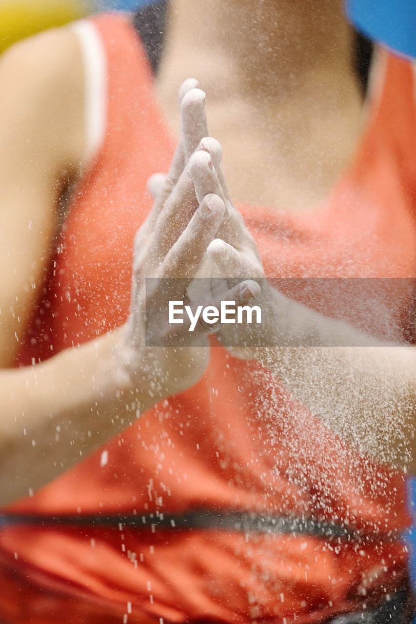 Midsection of woman with hands clasped by sand