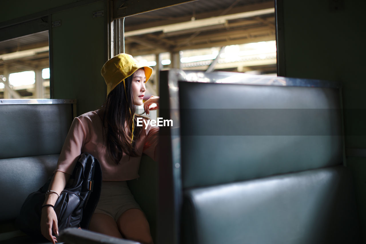 Woman looking through window while sitting in train