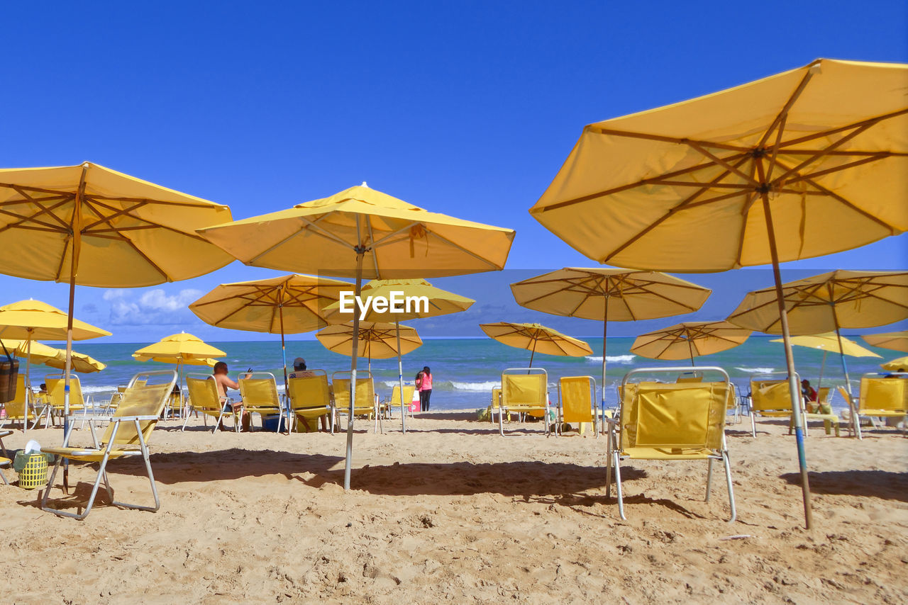 Umbrellas on beach against clear blue sky