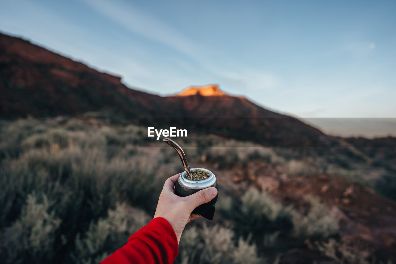 MIDSECTION OF PERSON HOLDING ICE AGAINST MOUNTAIN