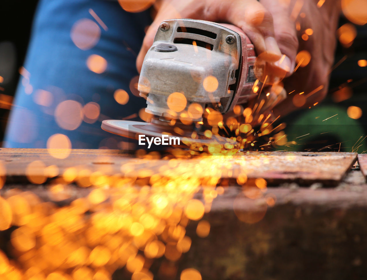 Midsection of man cutting metal