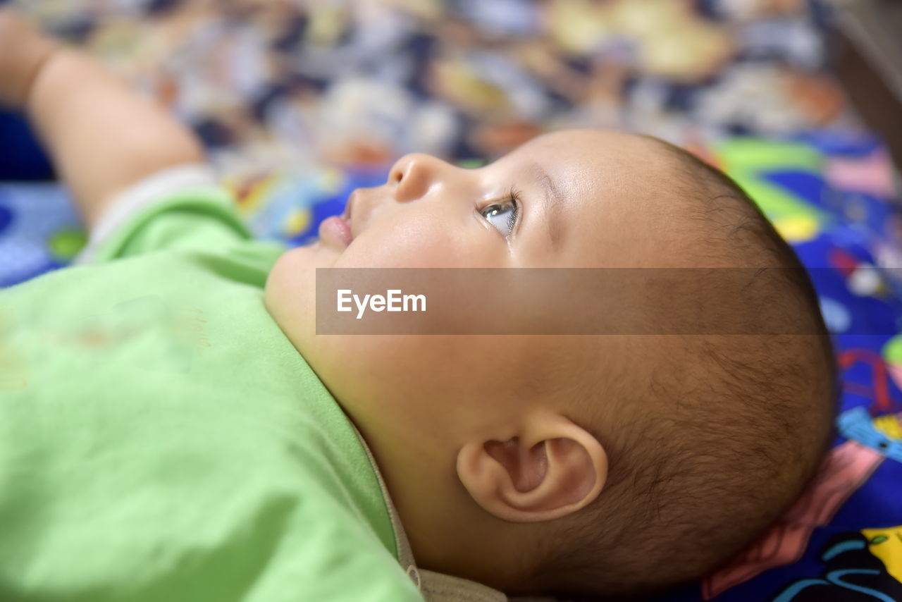 PORTRAIT OF CUTE BABY LYING DOWN ON BED