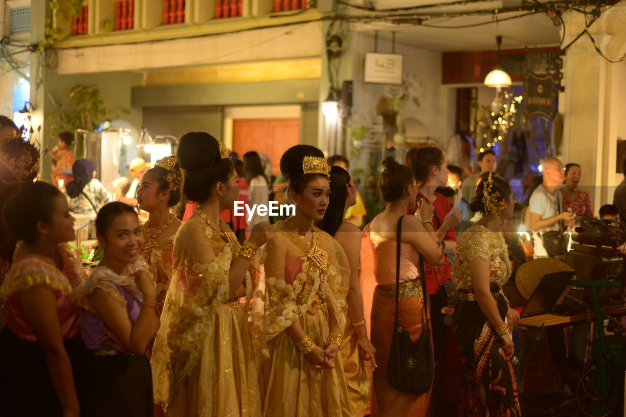 GROUP OF PEOPLE AT ILLUMINATED MARKET