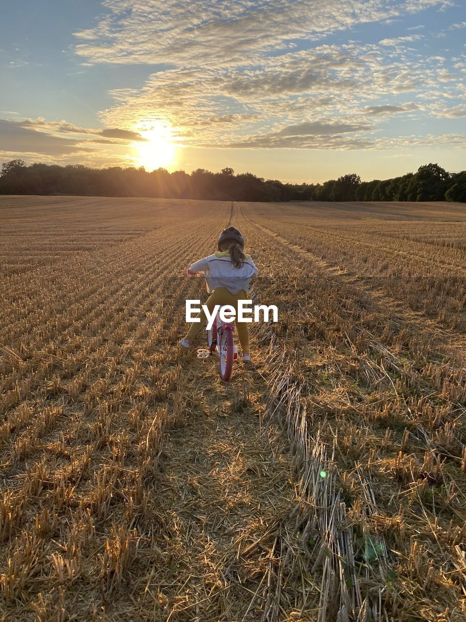 Girl standing on field against sky during sunset