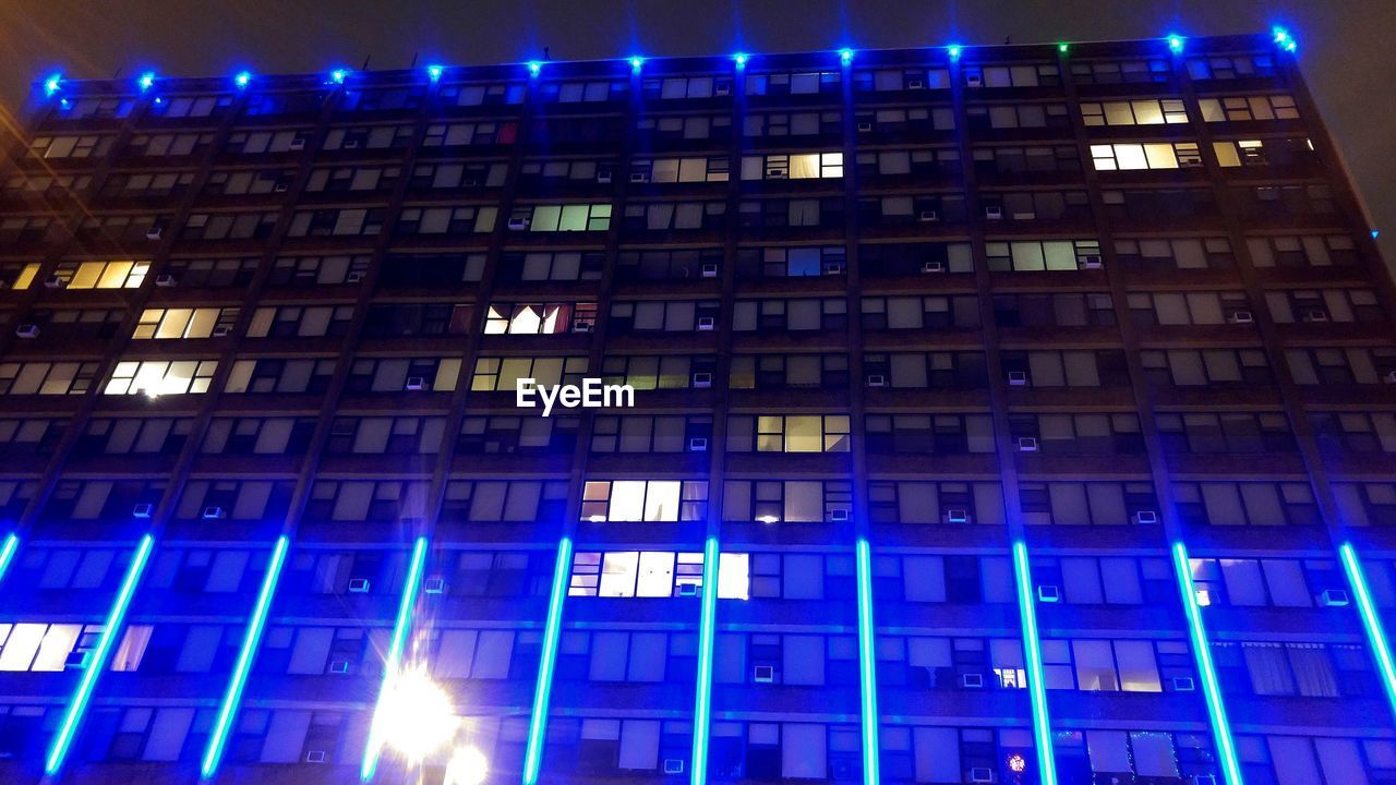 LOW ANGLE VIEW OF ILLUMINATED BUILDINGS AT NIGHT