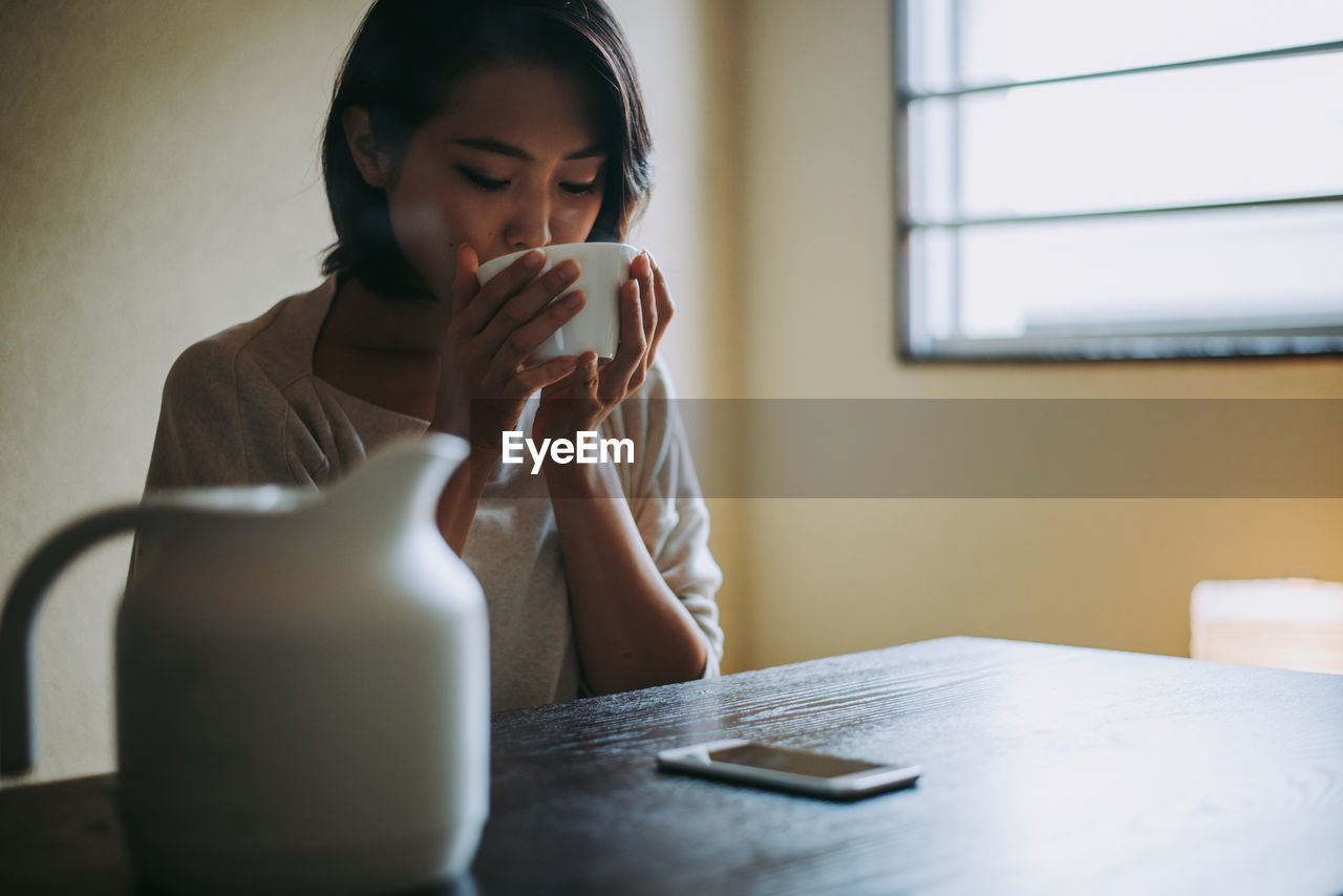 Woman drinking coffee while sitting at home