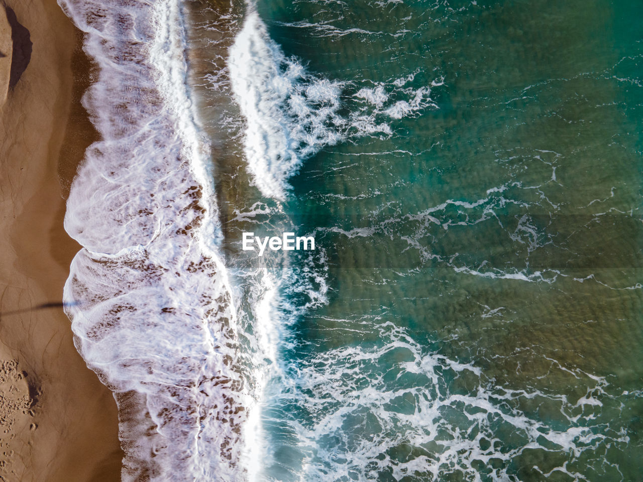 HIGH ANGLE VIEW OF WAVES BREAKING ON SEA