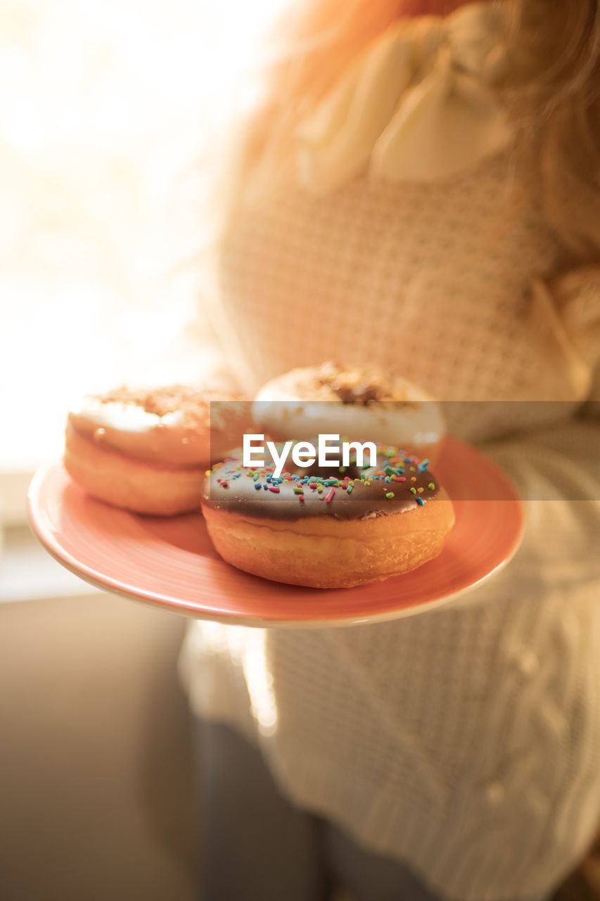 Tasty donut and holiday details, blonde girl holding plate with tasty donuts