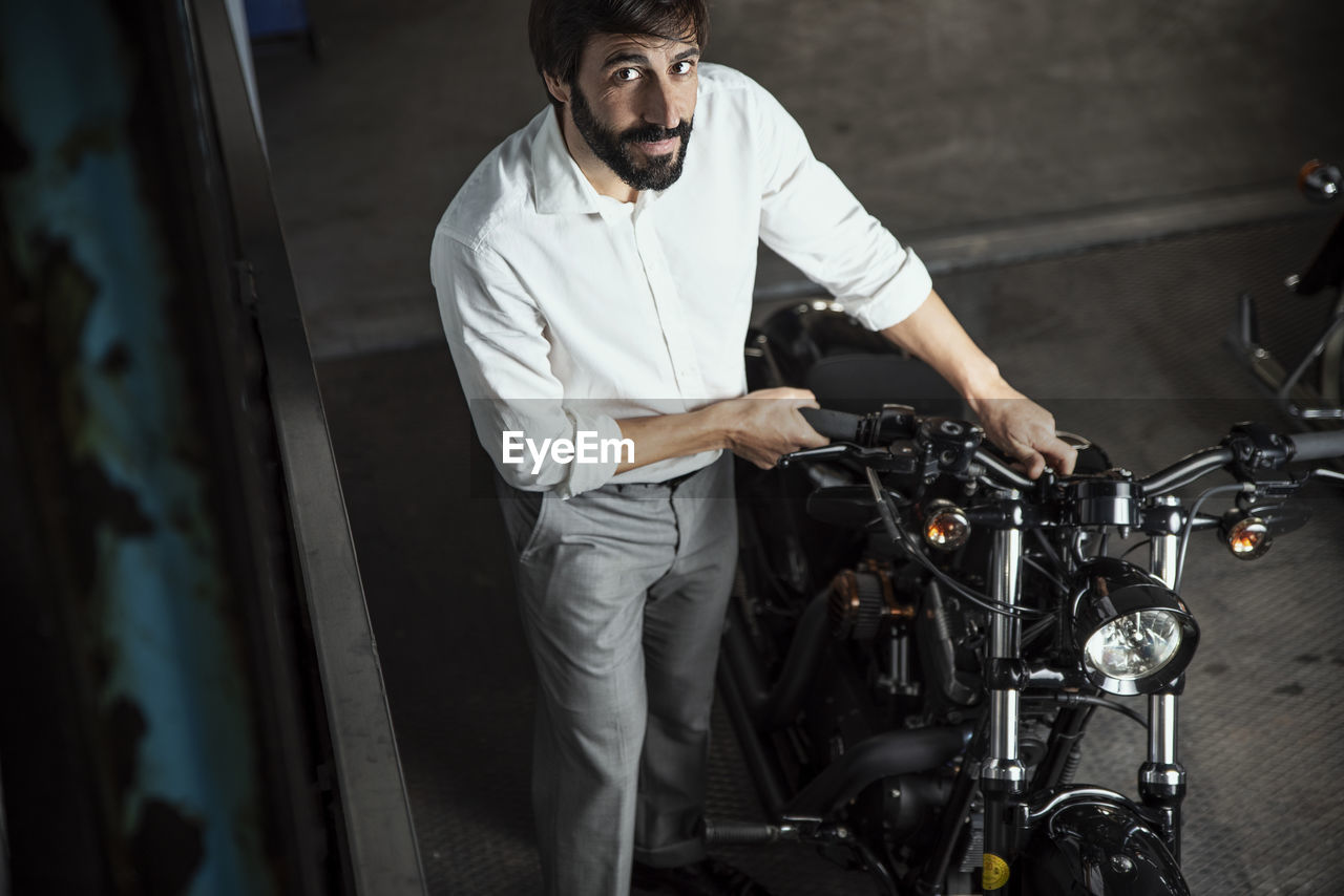 Portrait of businessman looking at motorcycle parked in garage