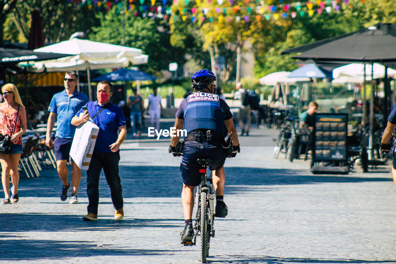 REAR VIEW OF PEOPLE RIDING BICYCLE ON ROAD